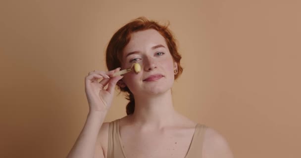 Ansiktsmassage Ingefära Kvinna Massera Ansiktet Med Jade Roller Skönhetsbehandling Beige — Stockvideo