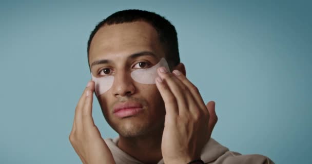 男人的漂亮脸蛋 眼皮底下有面具 美男子在面部皮肤上涂补丁 胶原面膜 高分辨度 — 图库视频影像