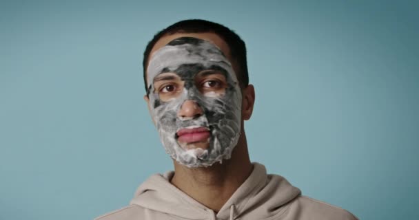 顔の治療 男性のためのスキンケア手順 スパのリラクゼーションの間に黒い顔のマスクを適用モデル 顔のケアのための美容泥 — ストック動画