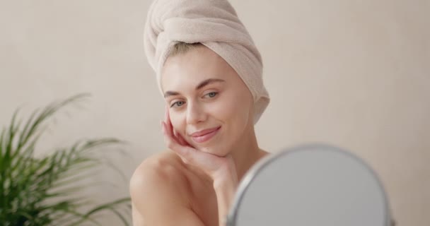 浴室でクリームを適用する魅力的な女性 ハッピーガール栄養面スキンケアクリーム治療を顔に 鏡を見て毎日朝の美しさルーチンを行う — ストック動画