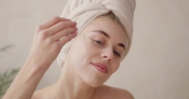 Kadın yüzüne serum döküyor. Avrupalı bir kız yüzüne pipetten serum kolajen nemlendirici sürüyor. Pozitif güzel kadın. Yüz bakımı kavramı 