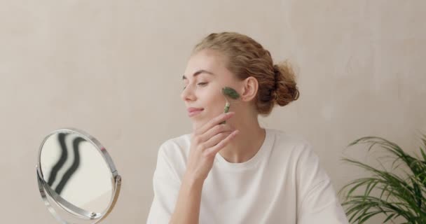 フェイスマッサージ 肌のケア 自宅での美しさの治療のための玉顔ローラーを使用して笑顔の女性 女の子使用ナチュラルマッサージクローズアップポートレート — ストック動画