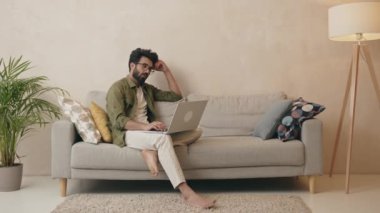 Ciddi bir adam internetten e-posta haberlerini kontrol ediyor. Kanepede oturuyor, sosyal ağlarda arkadaş arıyor ya da bilgisayarda çalışıyor, blog yazıyor ya da evde ders çalışıyor. 
