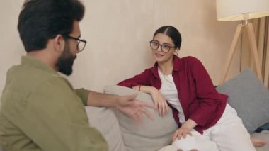 Kanepede konuşan ve flört eden neşeli Hintli çift. Kadın ve erkek evde vakit geçirmekten zevk alıyorlar. Mutlu evlilik ve romantik ilişki kavramı 