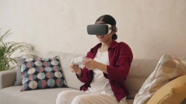 VR gözlüklü genç Hintli kadın heyecan verici oyunlar oynamak için joystick 'i kontrol ediyor. Rahatlama kavramı 