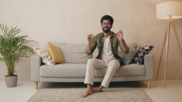 Joven Sentado Sofá Casa Sonriendo Feliz Positivo Mostrando Buen Gesto — Vídeos de Stock