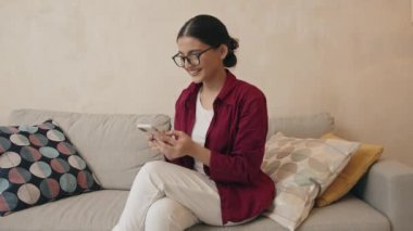 Gülümseyen Hintli kadın cep telefonu iletişiminden zevk alıyor oturma odasında hoş bir mesaj okuyor. Kız tutma aygıtı