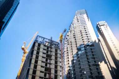 İnşaat vinci yüksek bir bina inşa ediyor. İnşaat asansörü insanları işe götürüyor..