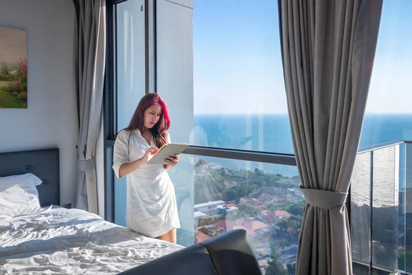 Businesswoman working at sea view hotel using tablet when traveling in Asia