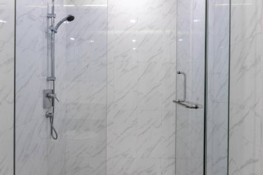 Banyoda paslanmaz çelik duş ve otel odasındaki beyaz mermer fayanslar.