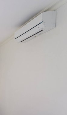 Beyaz duvar odasının arka planında klima var.
