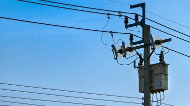 Arka planda mavi gökyüzü olan yol kenarındaki elektrik direğine yakın çekim.