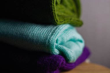 Farklı renklerde örülmüş rahat süveterler üst üste dizilmiştir.