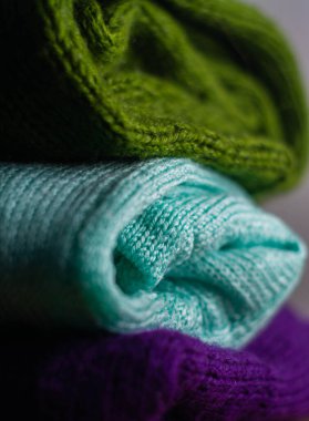 Farklı renklerde örülmüş rahat süveterler üst üste dizilmiştir.