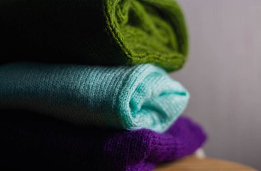 Farklı renklerde örülmüş rahat süveterler üst üste dizilmiştir.