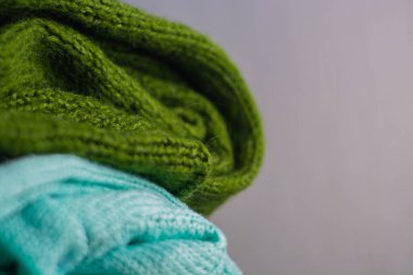 Farklı renklerde örülmüş rahat süveterler üst üste dizilmiştir.