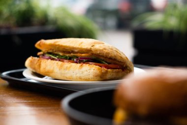 Large ciabatta sandwich with salad, fresh vegetables and onions, and meat.