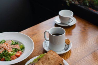 Full table of delicious and different dishes in cafe with cup of coffee in white dinnerware.