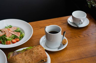 Full table of delicious and different dishes in cafe with cup of coffee in white dinnerware.
