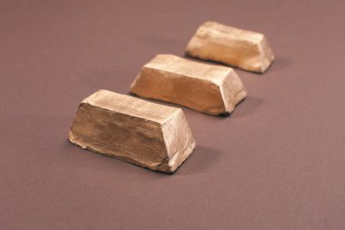 Kahverengi yüzeyde izole edilmiş altın çubuklar