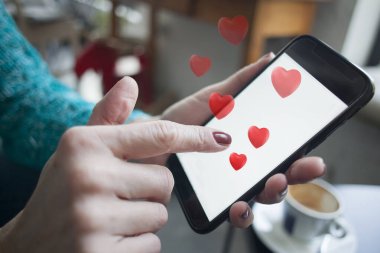 Kırmızı kalpli akıllı telefon kullanan bir kadın.