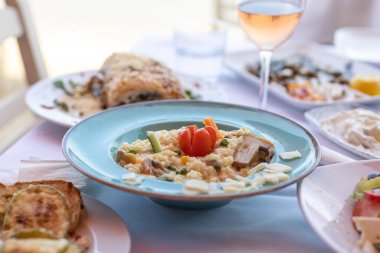 Sebzeli risotto tabağı yemek dolu masada servis edilir.