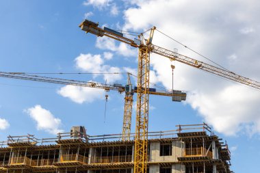 İnşaat vinçleri yeni alçak bina üzerinde çalışıyor