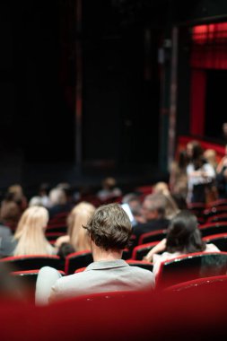 Sinemadaki insanlar yerlerinde oturuyorlar.