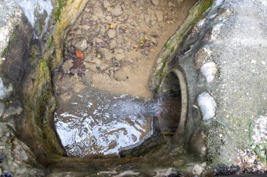 Bir dereye suyu boşaltan küçük beton menfezin yakın görüntüsü