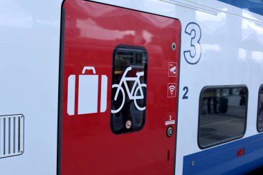 Gündüz vakti yoğun bir istasyonda bisiklet ve bagaj sembolleri bulunan modern Avrupa tren kapısı