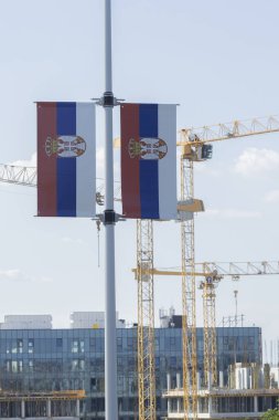 Sırbistan 'ın bayrakları, kentte gündüz saatlerinde kentsel gelişimi gösteren inşaat sahasının yakınında sergilendi