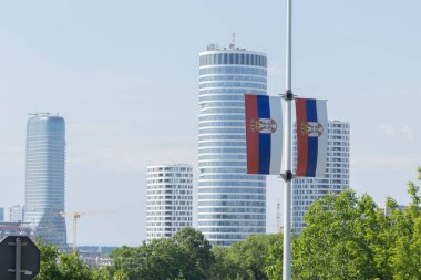 Modern Belgrad siluetine sahip bir direkte Sırp bayrakları sergileniyor