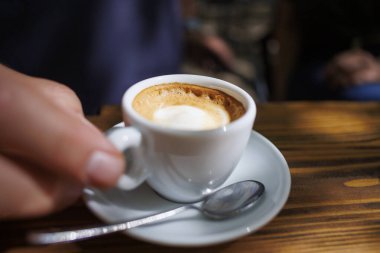 Tahta bir masada servis edilen bir fincan kahvenin yakın çekim görüntüsü.