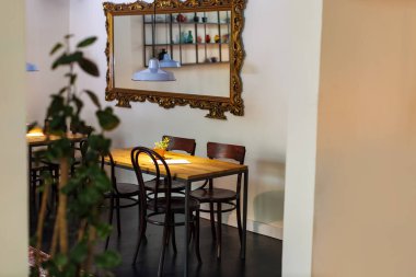 Süslü aynalar bir kafedeki ahşap masanın üzerine mavi lambalar yansıtıyor.