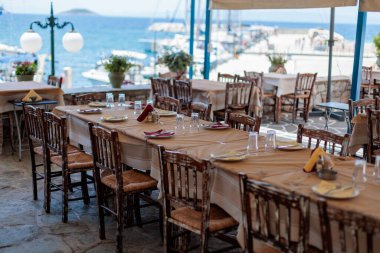 Okyanus manzaralı bir Yunan restoranında akşam yemeği için uzun bir masa.