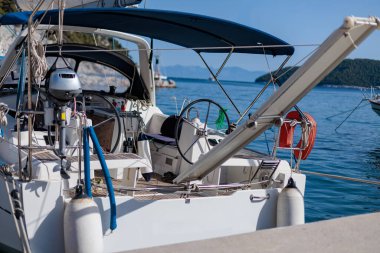 Güneşli bir günde beyaz yelkenli limana yanaştı.