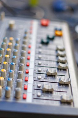 Gün boyunca bir açık hava müzik etkinliğinde renkli düğmeler ve kaydıraklarla ses karıştırma tahtasının yakın plan görüntüsü