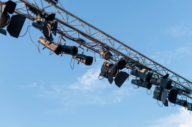 Sahne ışıkları açık mavi bir gökyüzünü aydınlatıyor. Öğleden sonraki açık hava performans kurulumu sırasında.