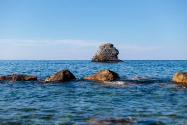 berrak bir gökyüzünün altında deniz suyundan çıkan bir sürü dev kaya.