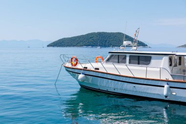 Güneşli bir günde adaların yakınındaki berrak mavi sularda demirlemiş motorlu tekne.