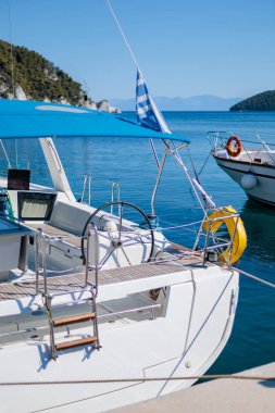 Yelkenliler güneşli bir günde berrak mavi sularla sakin bir marinaya yanaştılar.