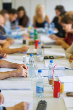 Büyük bir masada, modern bir çalışma alanında tartışan ve not alan katılımcılarla ortaklaşa beyin fırtınası yapmak.