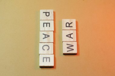 Barış ve savaş sarı arka planda tahta bloklarla yazılır.
