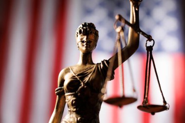 Adalet Anıtı, Amerikan bayrağı önünde kanun ve düzeni temsil eden teraziler tutuyor.