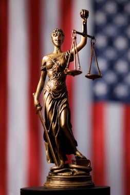 Adalet Anıtı, Amerikan bayrağı önünde kanun ve düzeni temsil eden teraziler tutuyor.