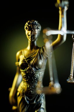 Bayan Adalet figürü sarı arka planda terazi tutuyor.