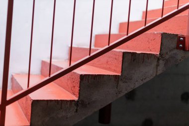 Parlak kırmızı korkuluklu merdivenler ve modern kapalı alan ortamında beton basamaklar.