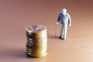 Bastonlu yaşlı adam, emeklilik birikimlerini ve finansal güvenceyi simgeleyen bozuk paraların yanında duruyor.