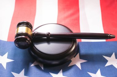 Gavel ve üssü Amerikan bayrağına dayanıyor. Mahkeme salonunda adalet ve demokrasiyi temsil ediyor.