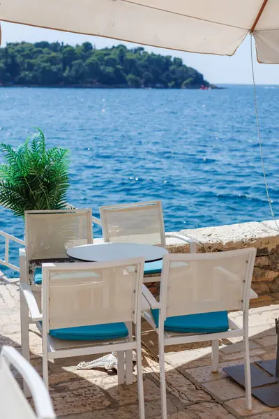 Güneşli bir günde sakin mavi suların kıyısında huzurlu bir sahil manzarası.